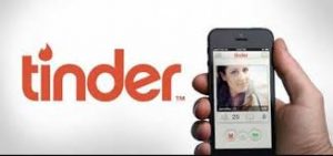 tinder logo alongside phone in hand